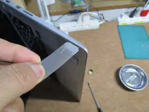隙間に薄いへらを差し込んで、止めを外している。