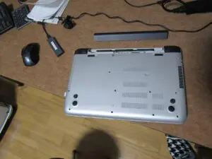 パソコンを裏返してバッテリーを外している写真