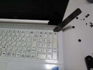 キーボードの隙間にヘラを挿しこんでいる